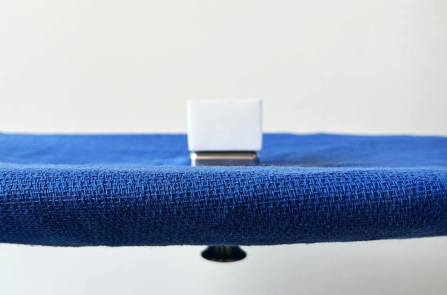 A close view along the edge of a blue-draped surgical tray with the white HypoHolder block standing at its centre