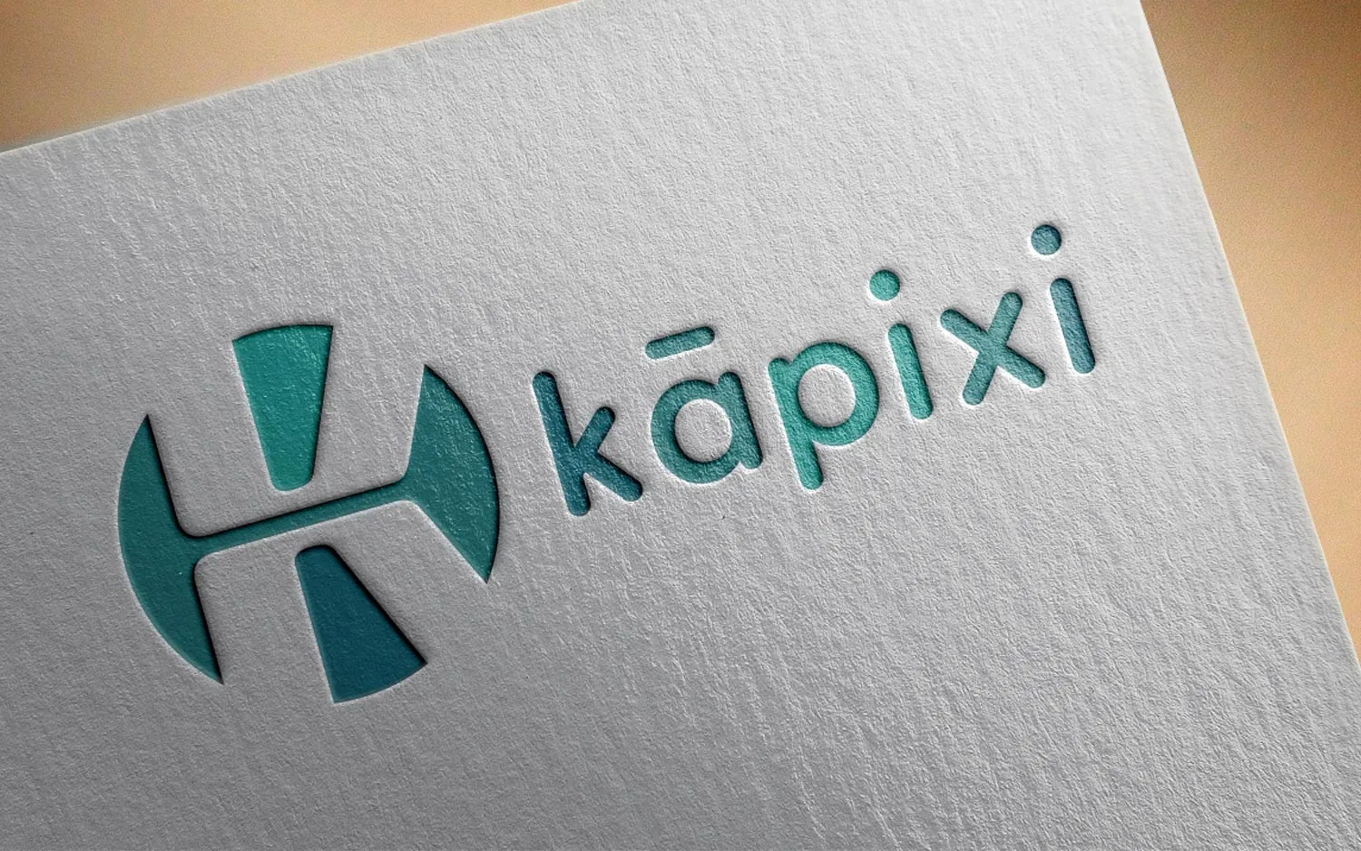 The Kapixi wordmark and circular mark letterpressed into textured white card