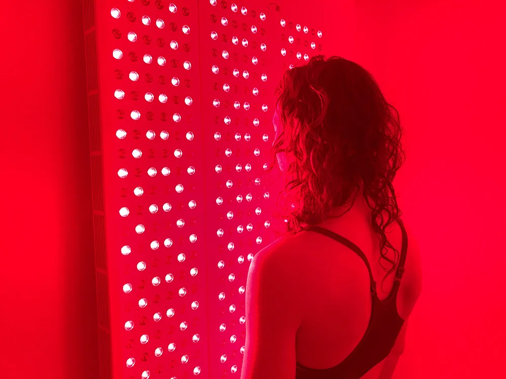 The red-light room in use, a client standing before the lit panel