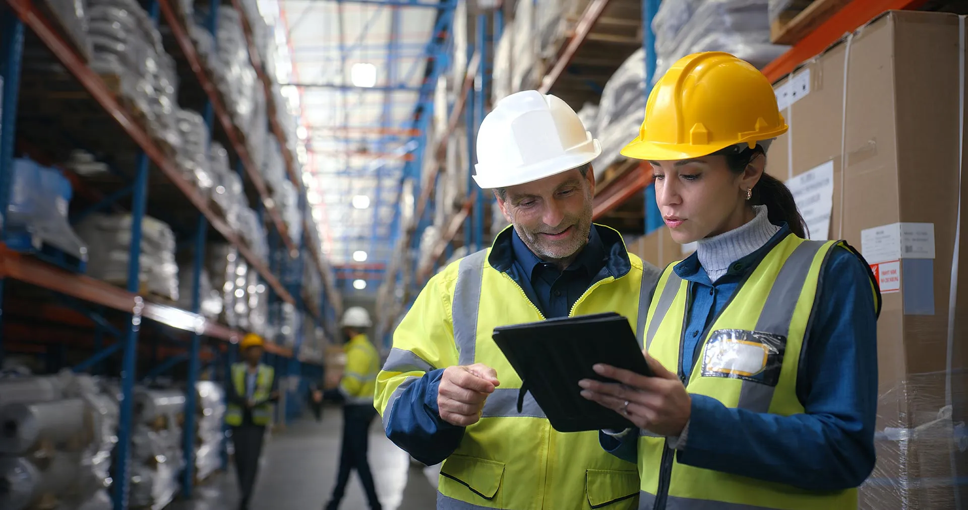 GMG EnviroSafe — warehouse workers in protective gear reviewing safety and compliance information on a tablet